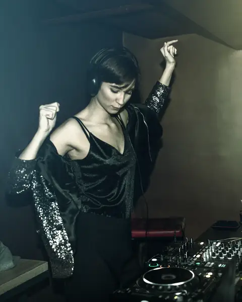Female DJ dancing behind Pioneer DJ decks in the studio