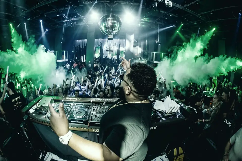 DJ performing to a packed Afrobiza Music Festival crowd under green lasers and smoke